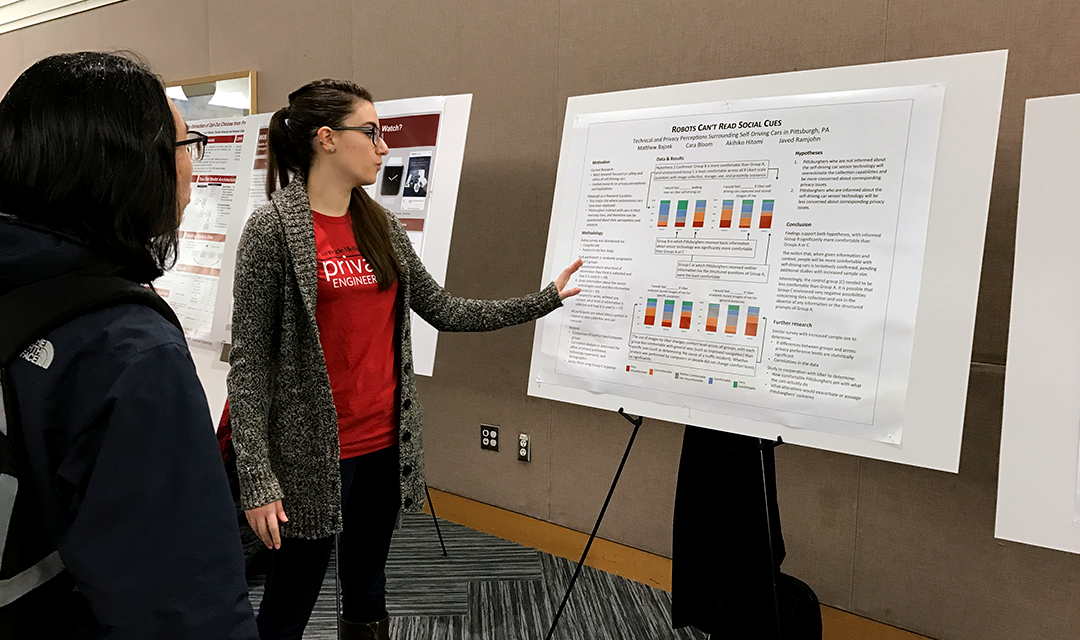 Student pointing to poster and explaining to other student