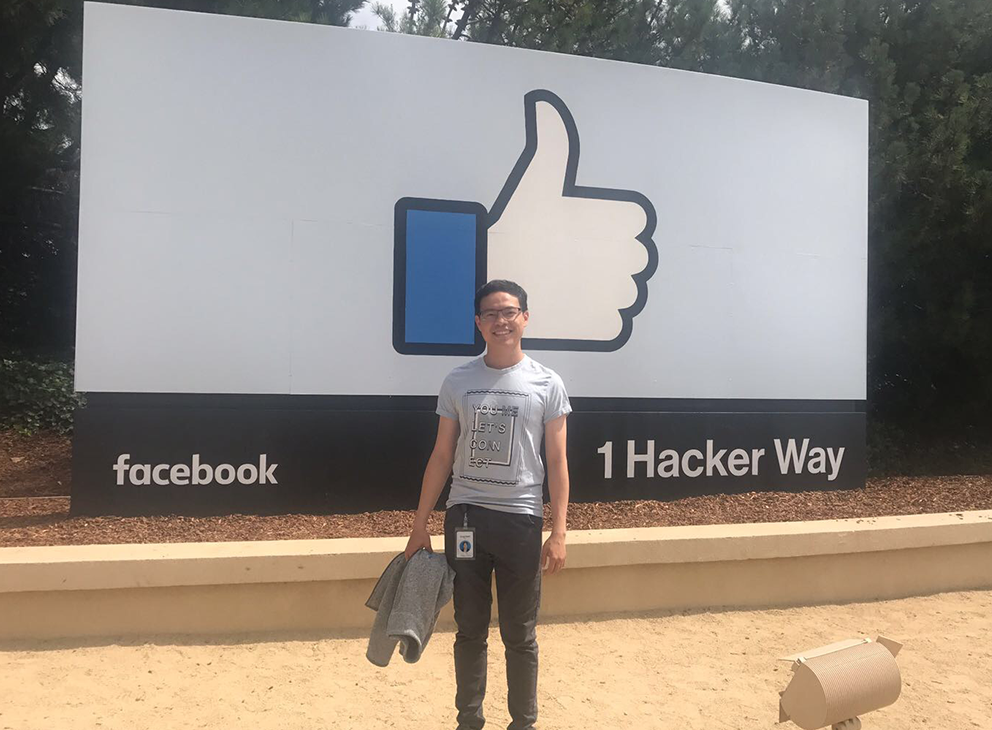 INI student poses in front of Facebook sign at summer internship