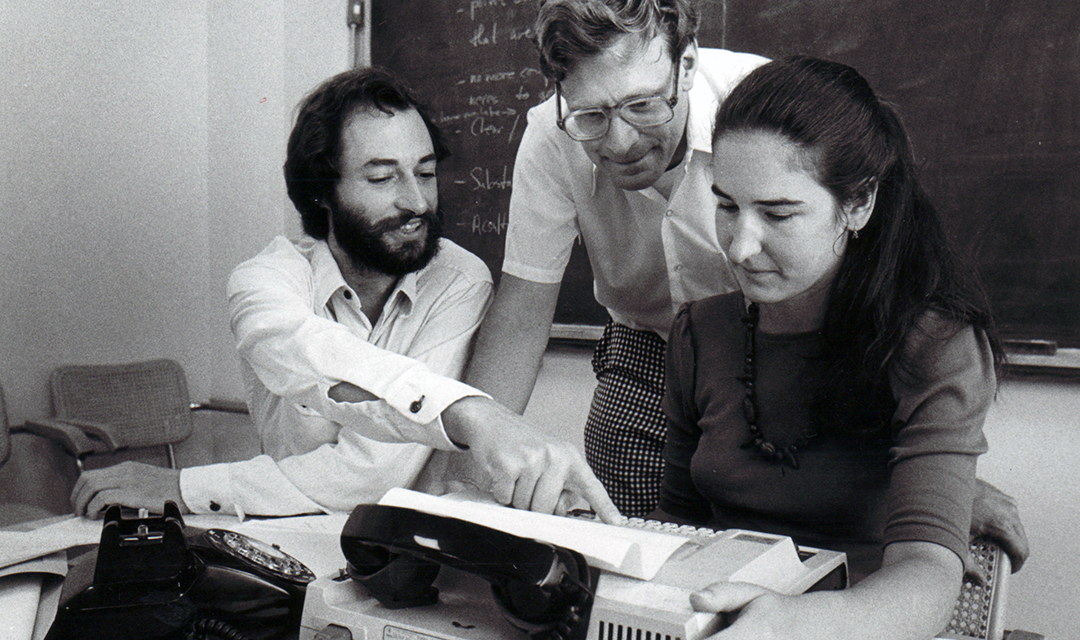 students and professor work on a typewriter in black and white