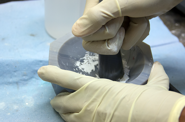 Hands crushing chemicals with mortar and pestle