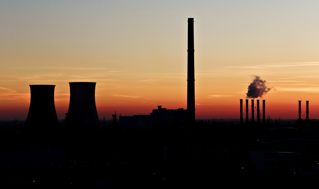 Silhouette of power plant, sunset in background