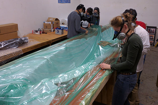 Students prepare the mold for the boat