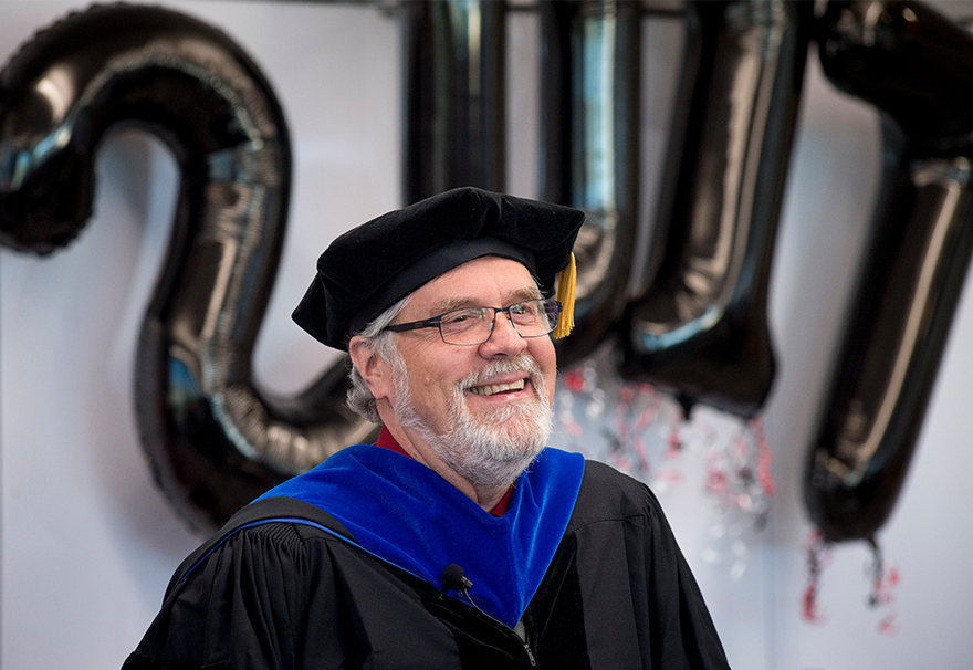 Landis in graduation robes in front of 2017 balloons