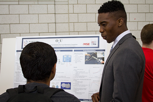 Student talking beside research poster
