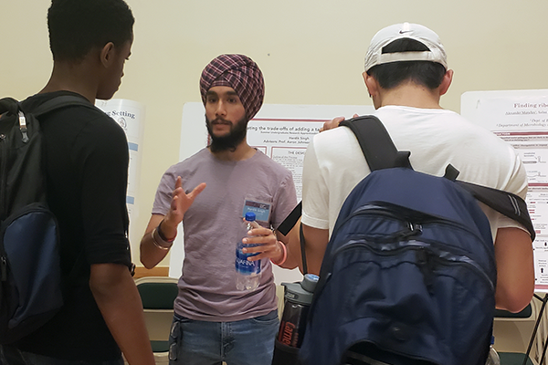 Student talking beside research poster