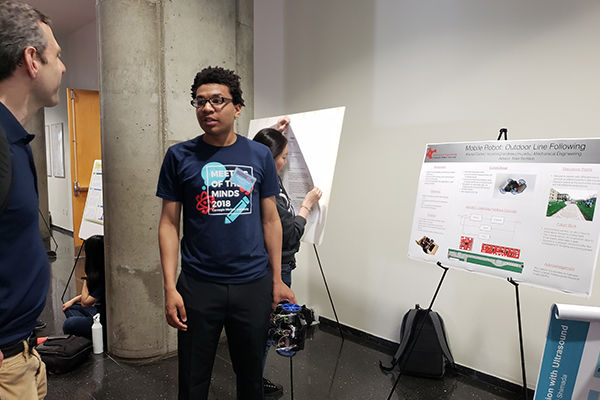 Student talking beside research poster