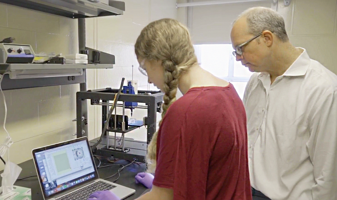 A man and a young woman in a lab looking at a computer screen