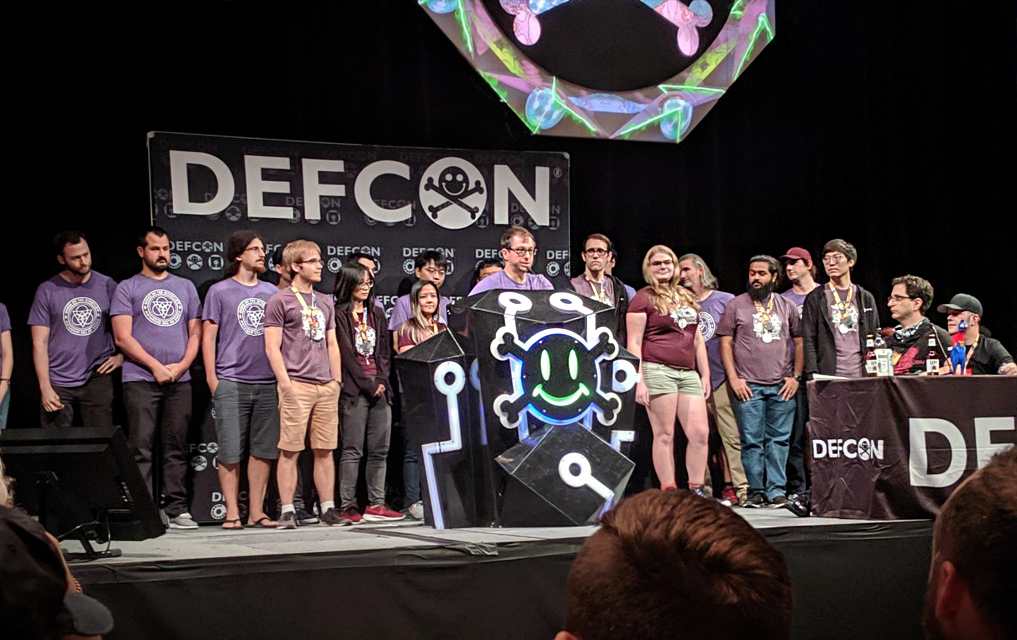 A group of students on a stage behind a man who is speaking