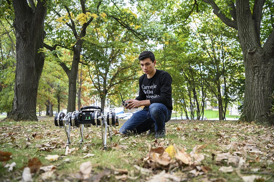 Vinay Mitta outside in a park with the Minitaur robot