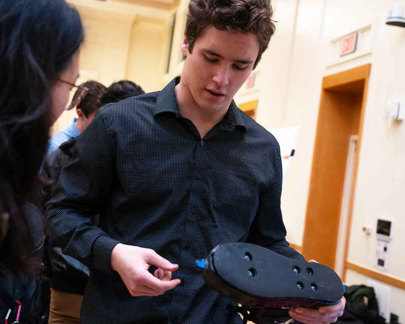 A student holding a shoe while talking to another student