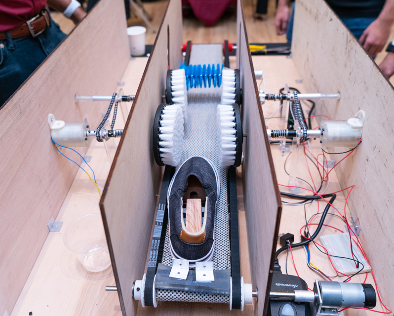 A show on a conveyor belt with brushes on the sides