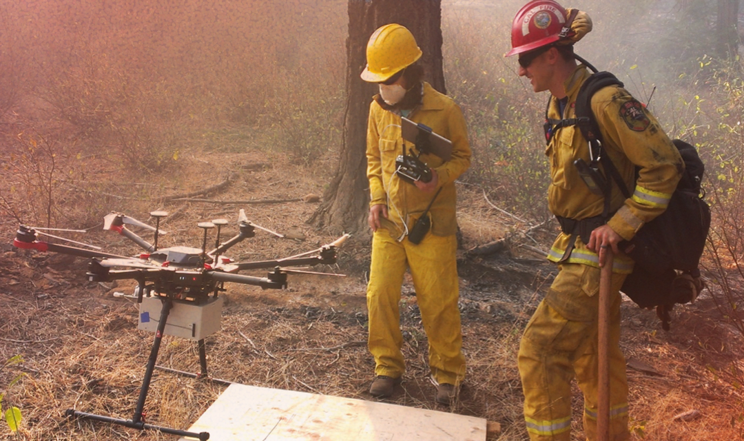 Professor Jen and CAL firefighter standing next to the airborne smoke collection drone during prescribed burns at Blodget Forest Research Station 2017. 