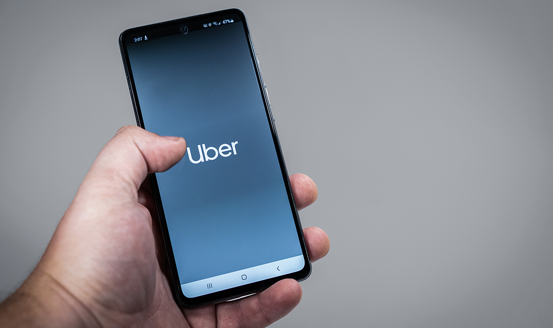 Hand holding a smartphone with the Uber app opening