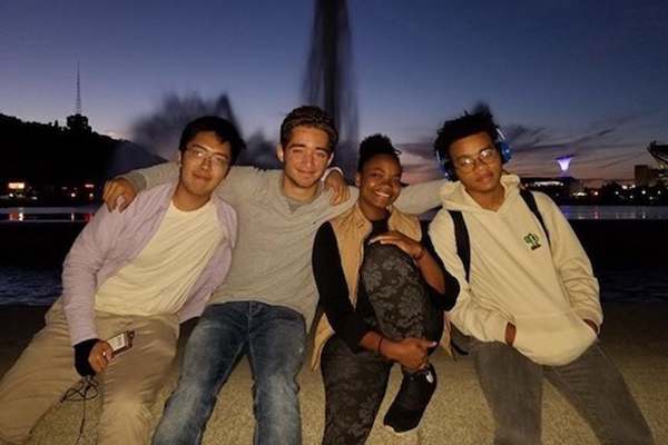 Four students sitting outside at sunset