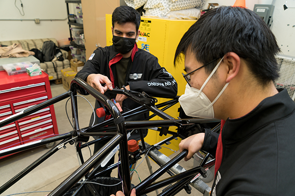 Two students working on part of the racecar