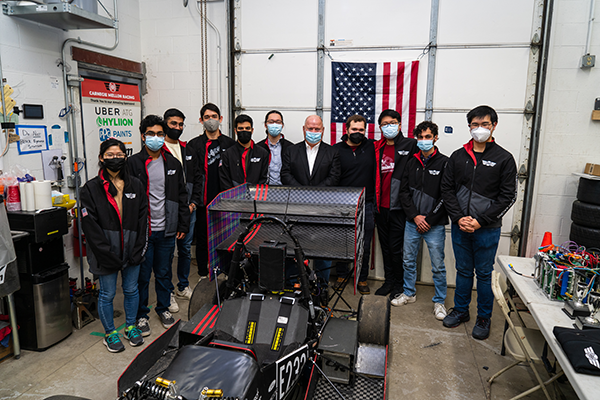 Group shot of students with Chip Ganassi and the racecar