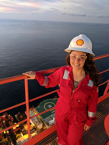 Young woman at the railing of a floating platform with the ocean behind her