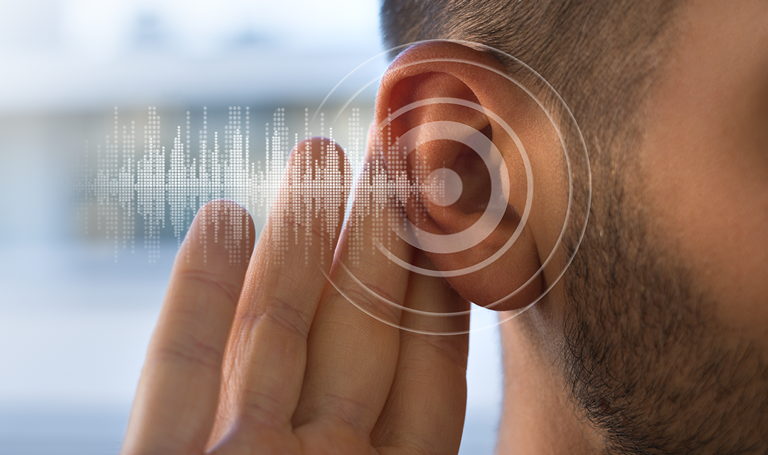 Hearing aid in someone's ear with sound waves moving through the air