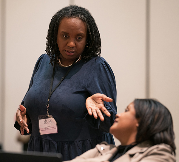 A woman gesturing animatedly while speaking with another woman