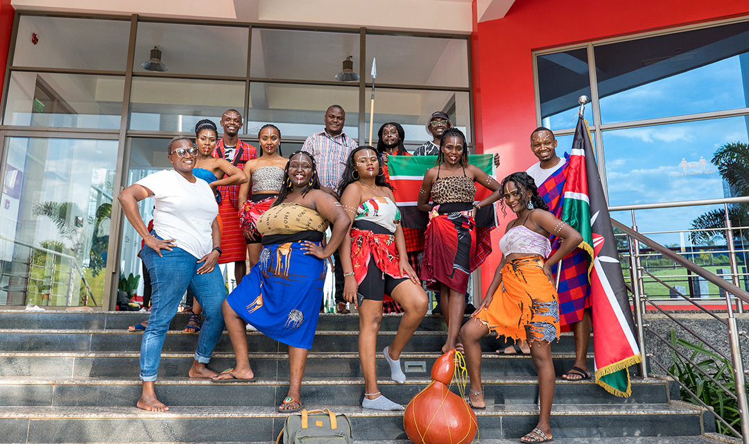Students in traditional African garb and makeup, standing on a set of stairs