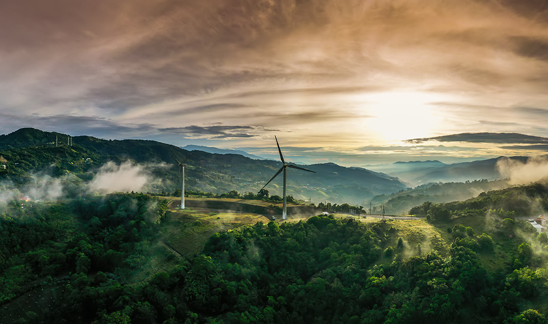 Windmills on a verdant countryside at sunset