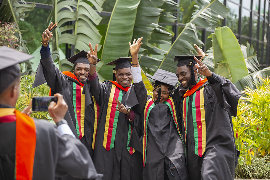 Four CMU-Africa students at graduation posing with their hands in the air