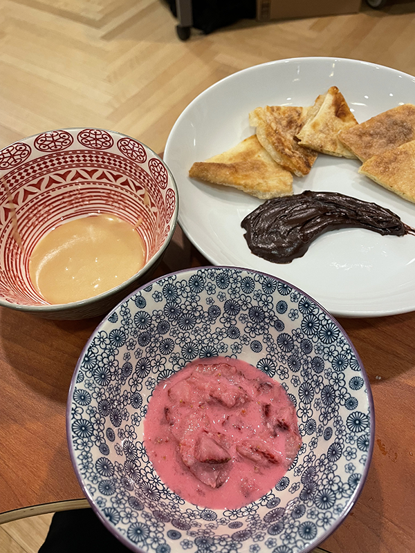 Three plates: one bowl containing a red sauce, another with a caramel-colored sauce, and a third with a pastry and chocolate smear.