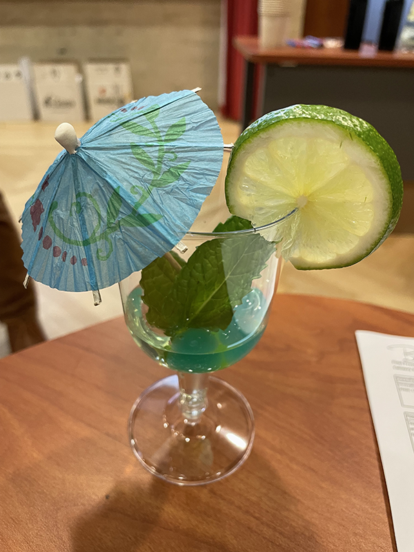 A tropical blue beverage with a lime and umbrella