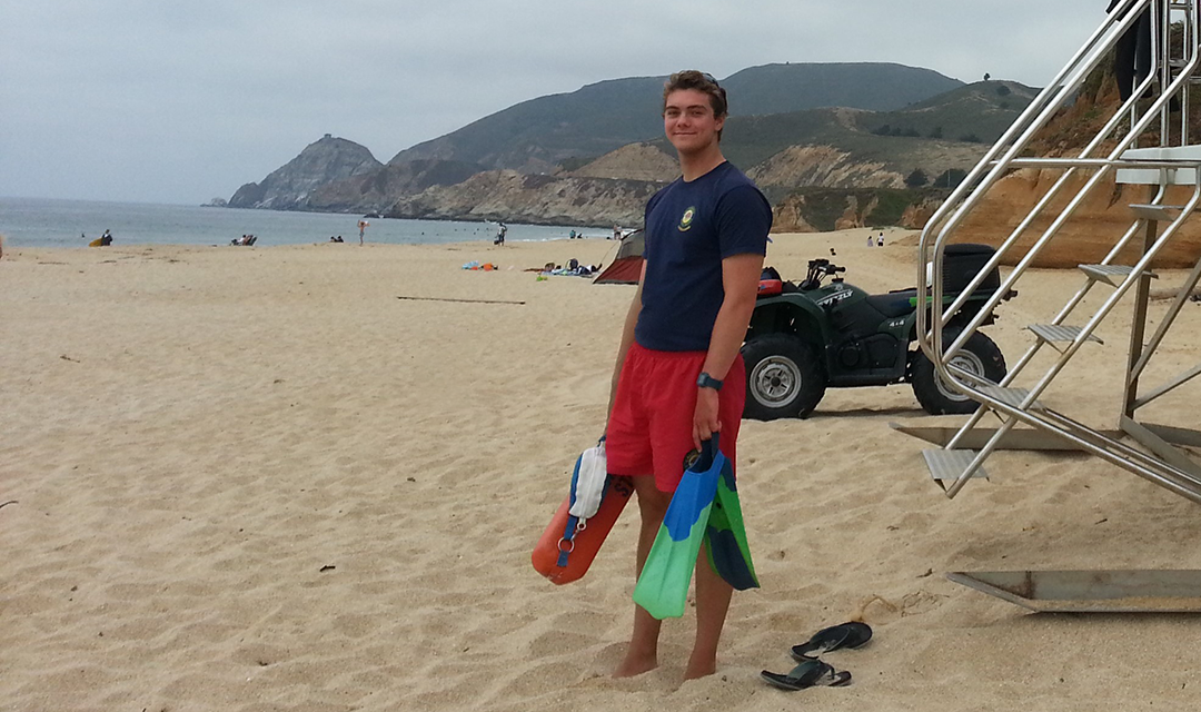 Kelby Kramer on the beach holding flippers