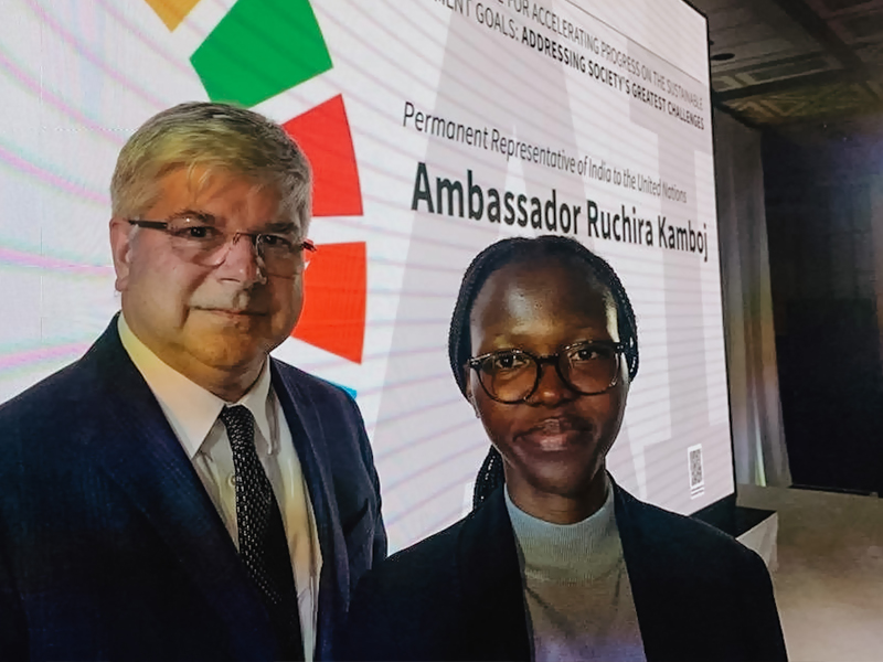 Dean Sanders and Choukouriyah Arinloye in front of a slide at the UN briefing