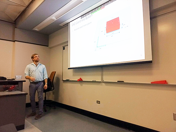 A man standing at a podium looking up at a powerpoint presentation