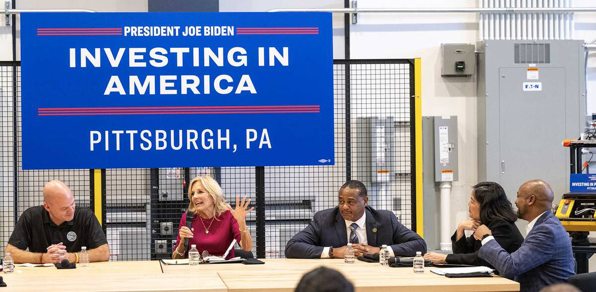 Jill Biden and Julie Su at a table talking with three men