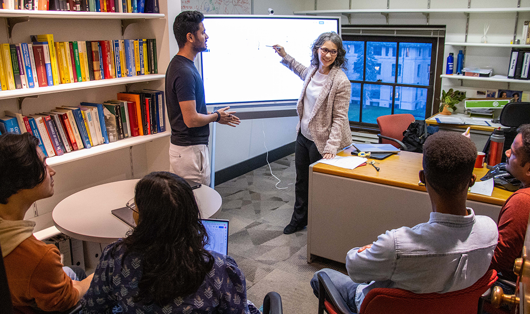 Anna Torres teaching a class, pointing to a projected screen