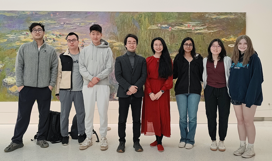Eight students standing in front of a watercolor painting