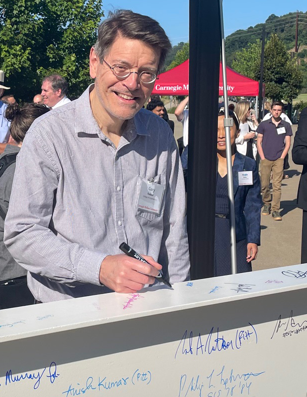 Man writing his name on a steel beam