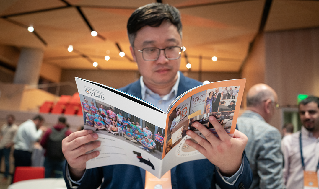 A man reading the CyLab Year-In-Review magazine