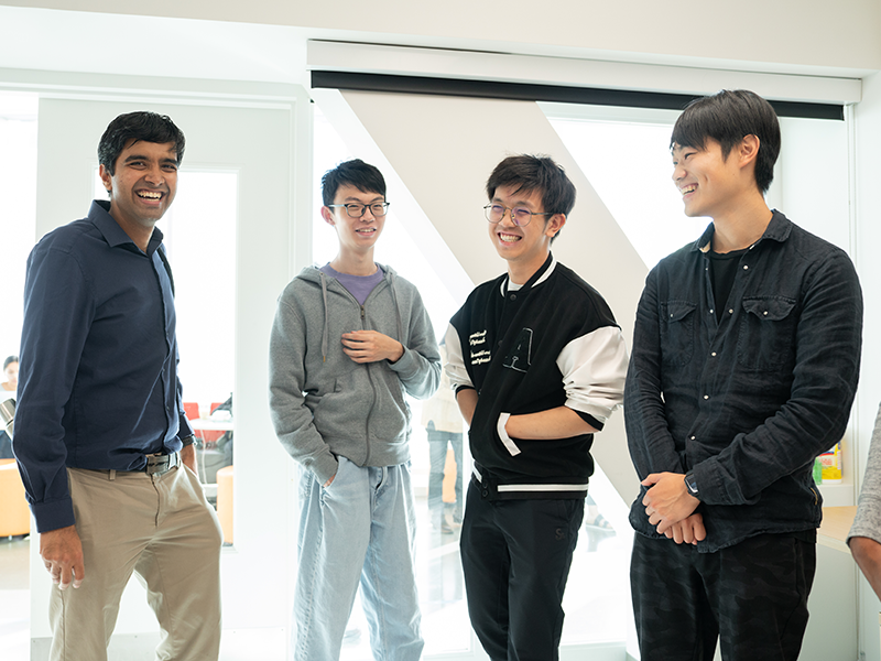 Four men standing together in a conference room.