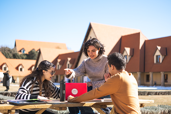 Three students working outside on a laptop