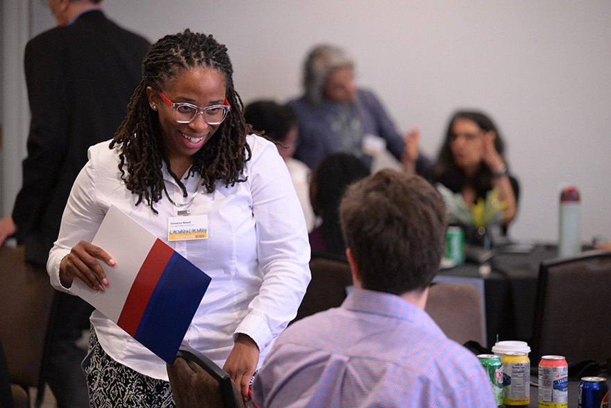 A black female standing and speaking with a seated person