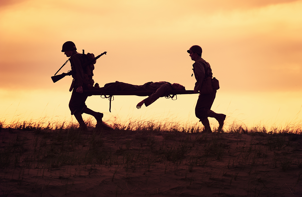Silhouette of soldiers carrying an injured soldier on a gurney