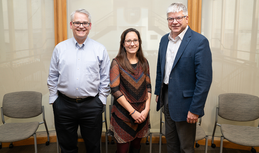 Two men and a woman (center) standing for a posed photo