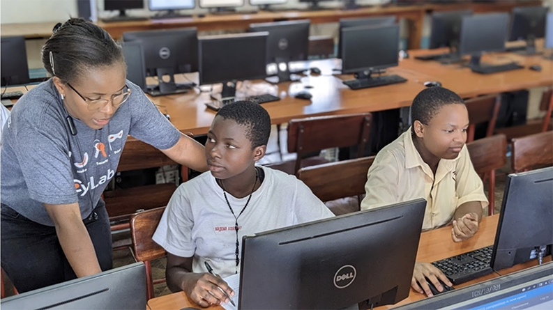 A teacher with two young students who are working on a computer