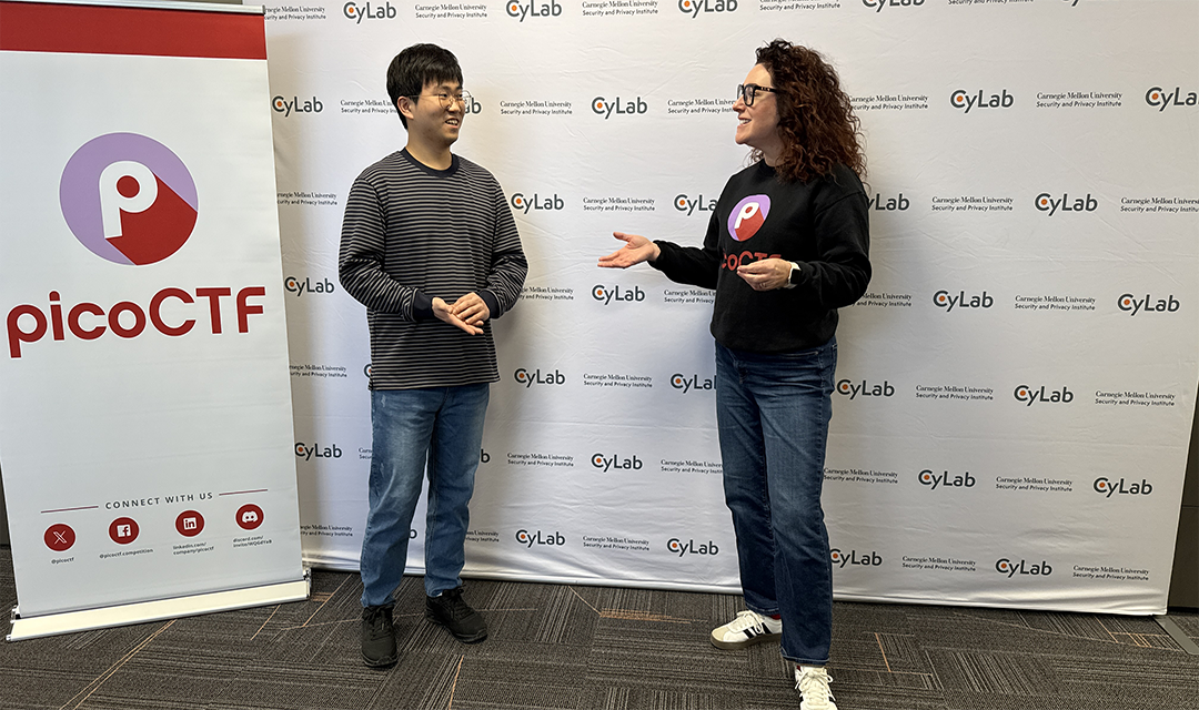 Two students chatting in front of a PicoCTF banner