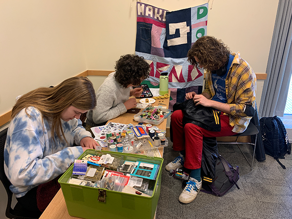 Three students working closely on a mending project