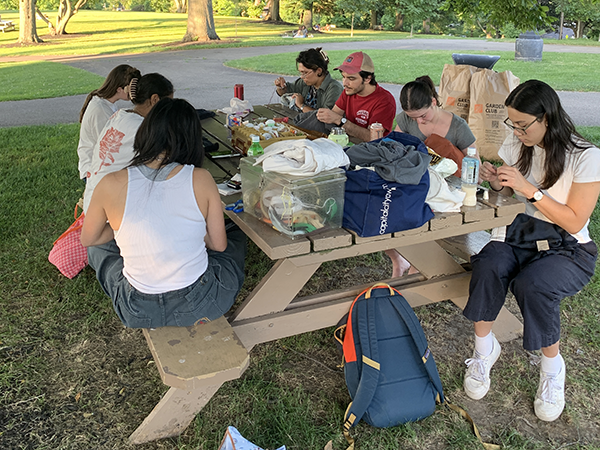 Students outside mending at a picnic table