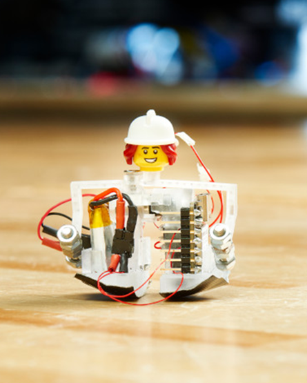 A miniature walking robot with actuators for feet and a lego head and hardhat