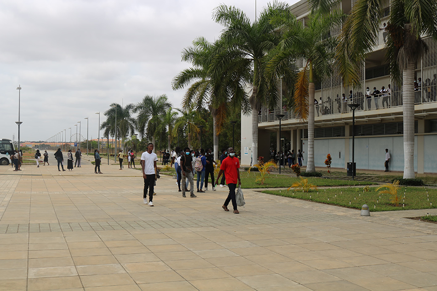 People walking down a large sidewalk along a building