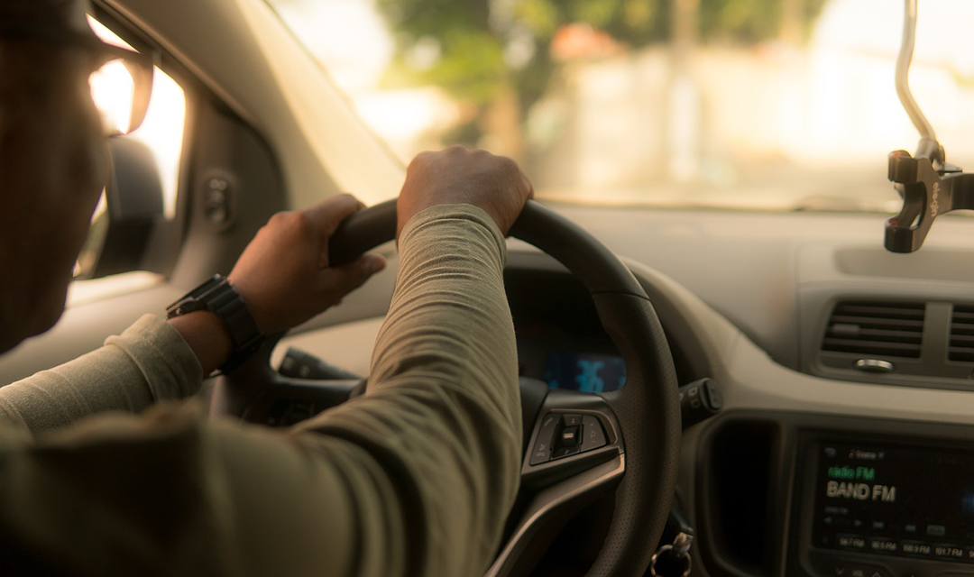 Interior of a car with view of hands on steering wheel and out windshield