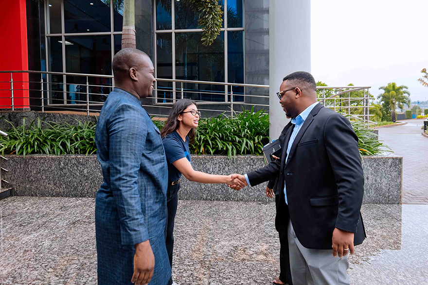 A man and a woman stand facing another man. The woman and the man opposite her are shaking hands.