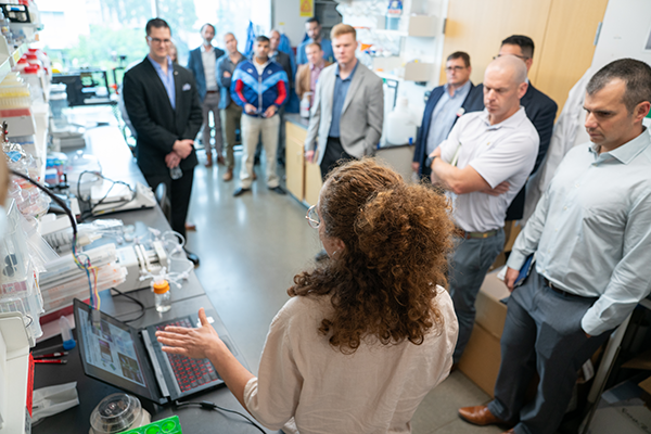 A woman in a lab speaking to a group of people